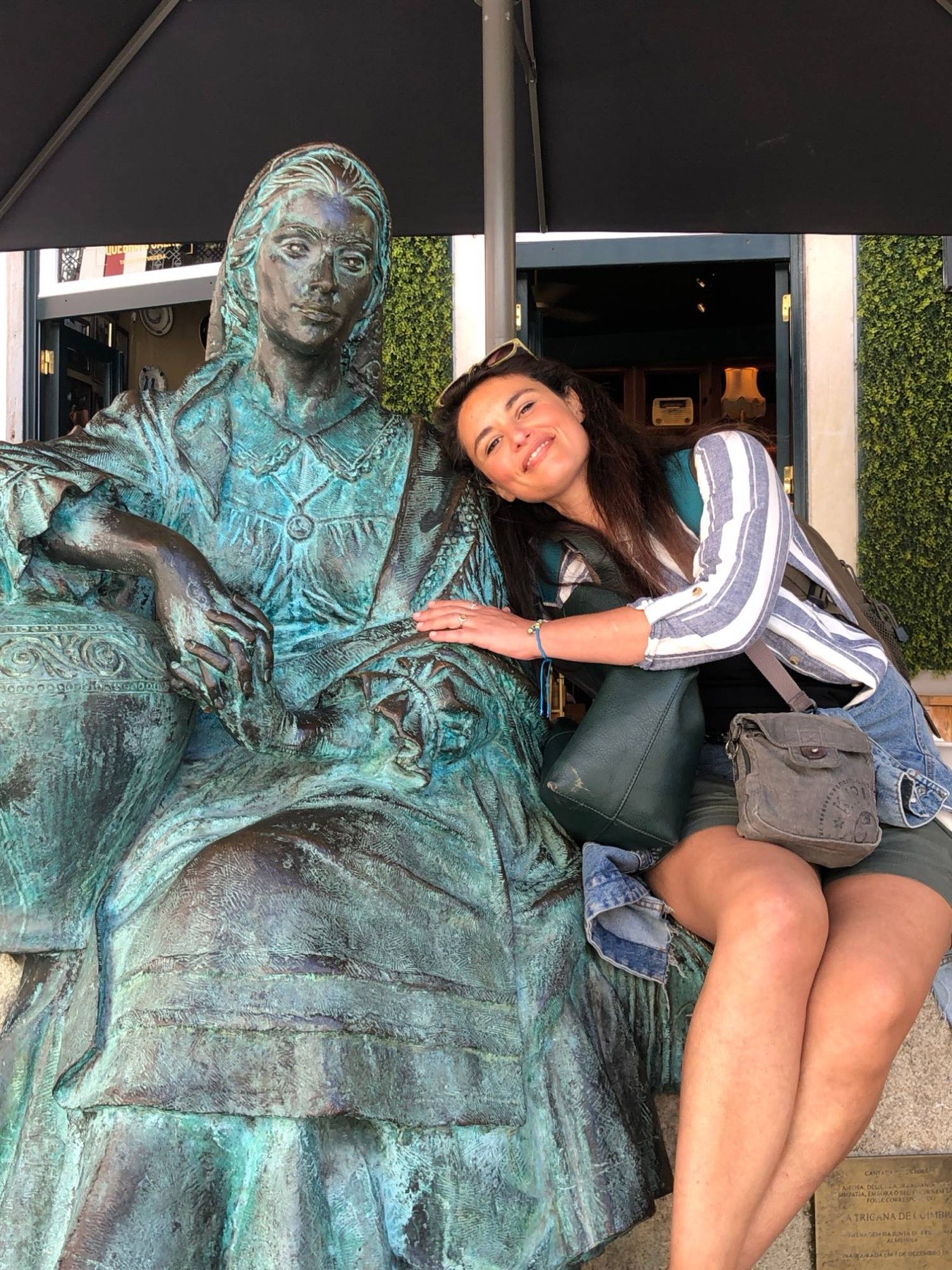 Ines leaning fondly on the shoulder of a bronze statue of a seated woman