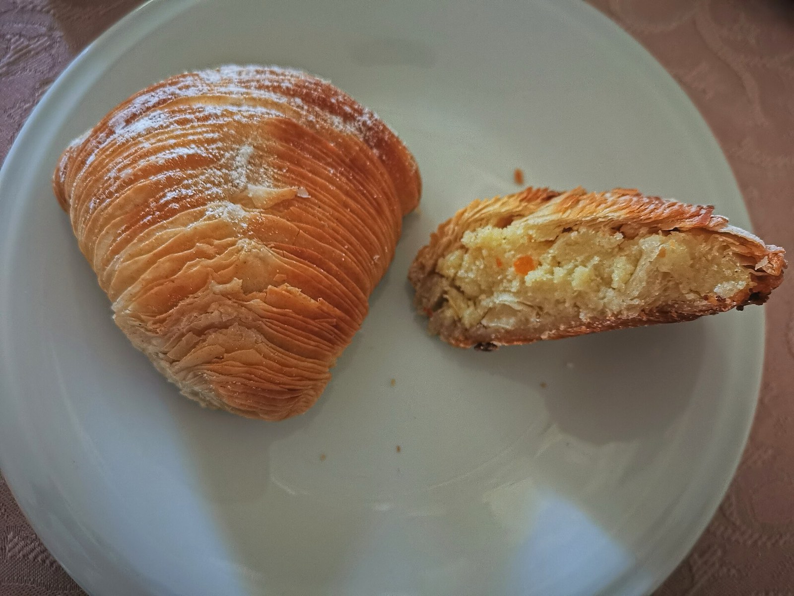 A sfogliatella riccia on a plate, one cut open to show the ricotta filling